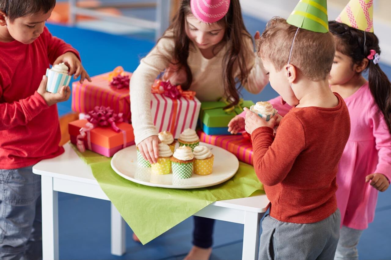Children celebrating a Gymboree birthday party with cupcakes and gifts